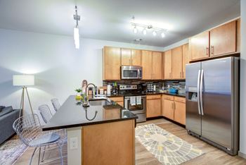 A kitchen with wooden cabinets and a black countertop at Regatta Sloans Lake Apartments, Denver, CO